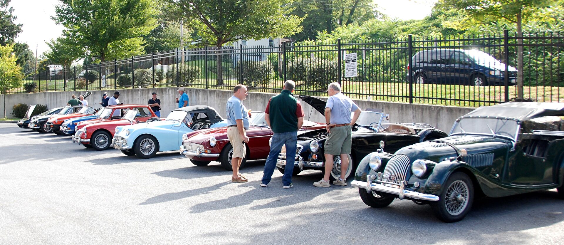 A group of men standing next to classic cars.