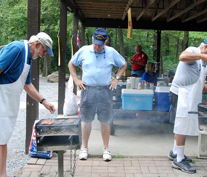 A group of men standing around a grill.