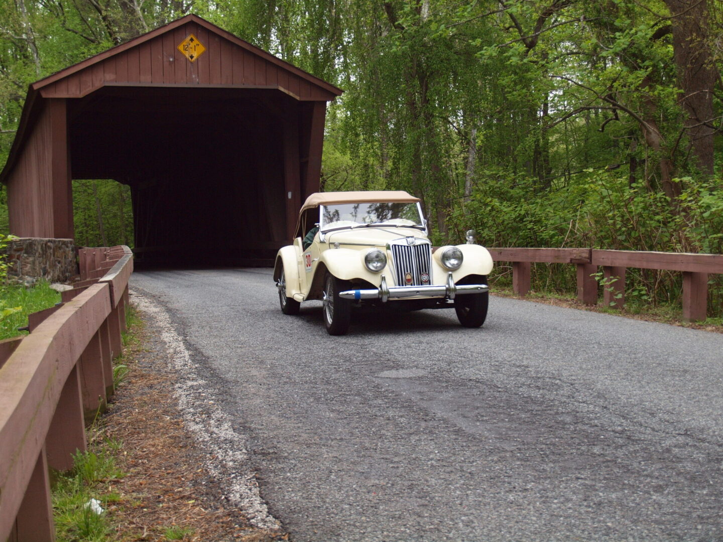 A car driving down the road under a covered bridge.