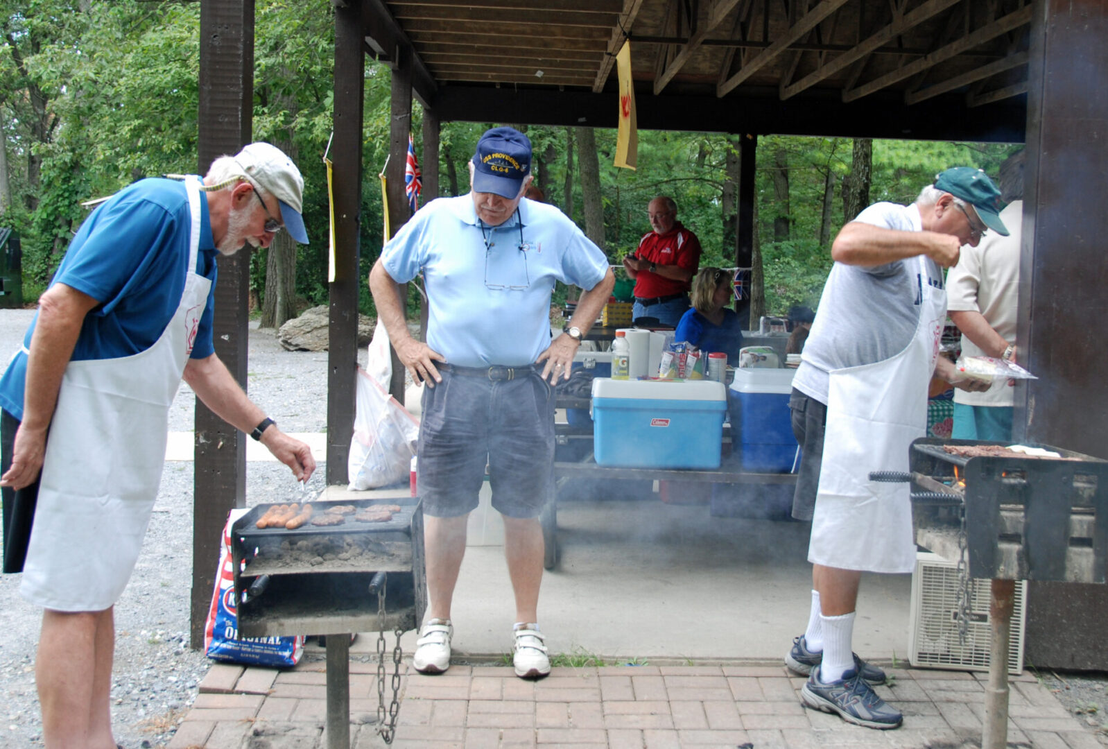 A group of men standing around a grill.