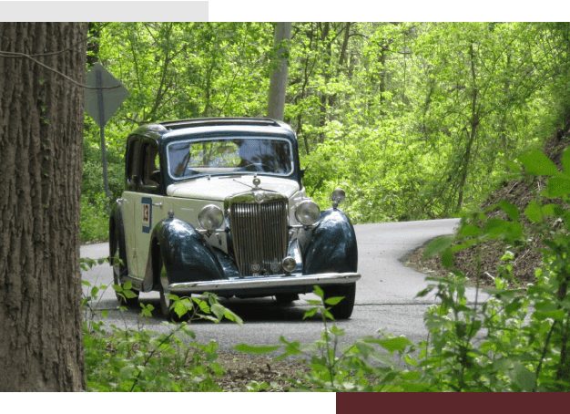 A car driving down the road in the woods.