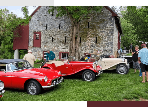 A group of old cars parked in front of a barn.