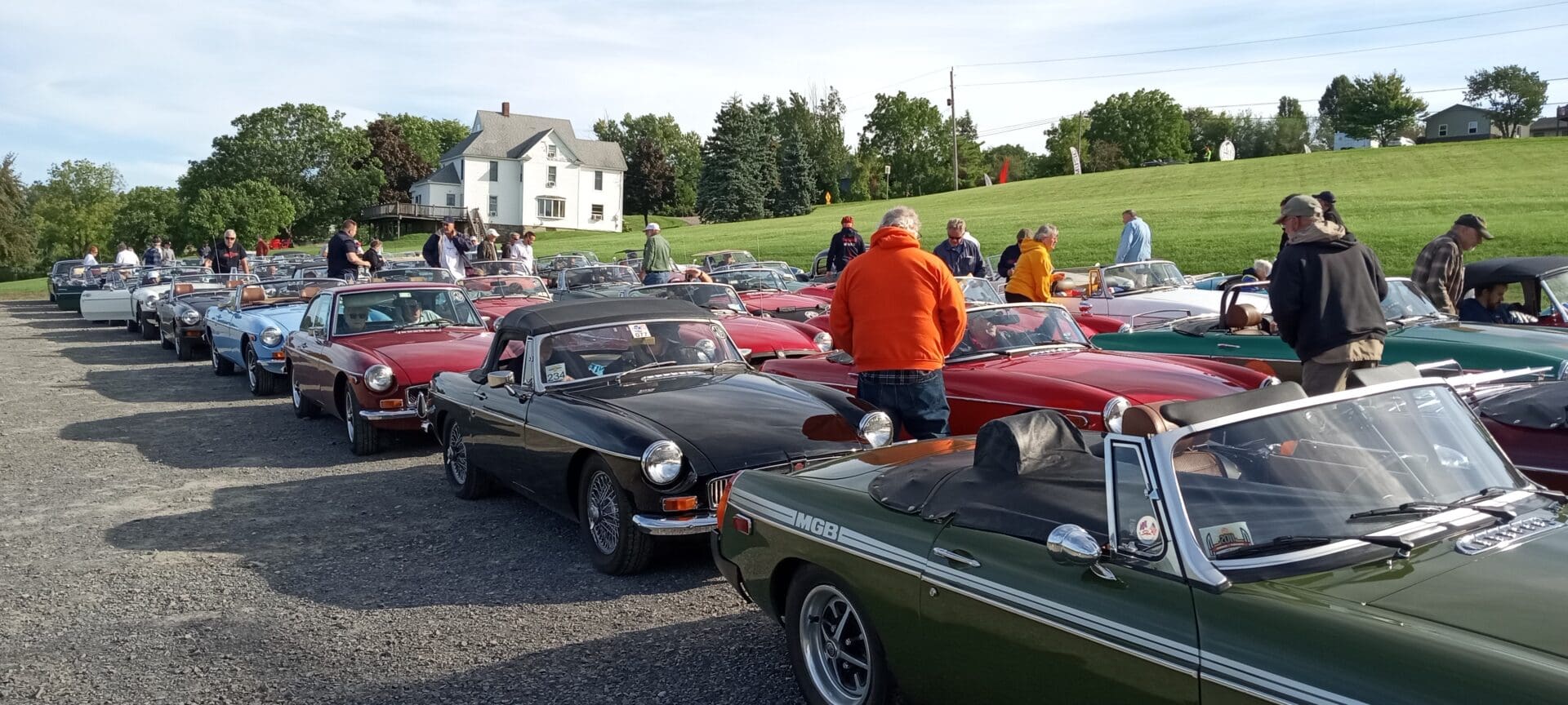 A group of classic cars parked outdoors with people mingling nearby.