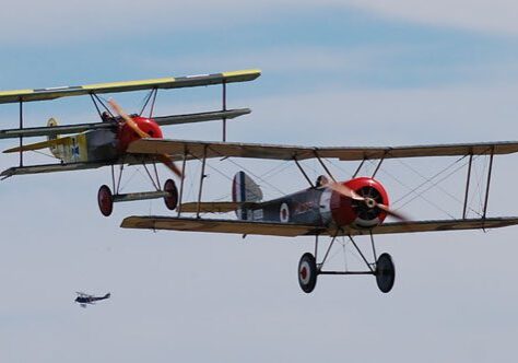 Two vintage biplanes flying in formation.
